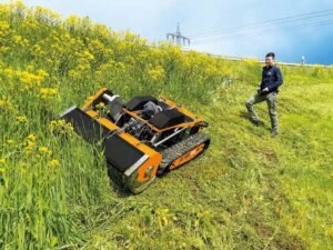 Man operating remote-controlled mower in grassy field