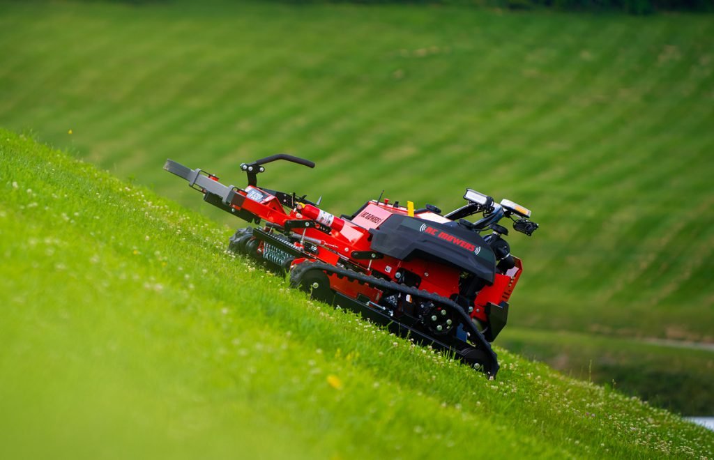 Red autonomous robot mower on vibrant green hillside